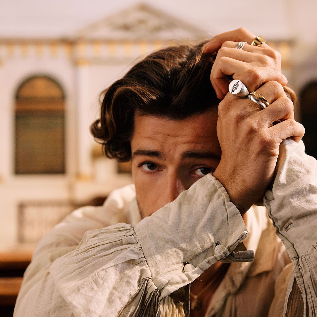 Man adjusting his hair with a blurred architectural background