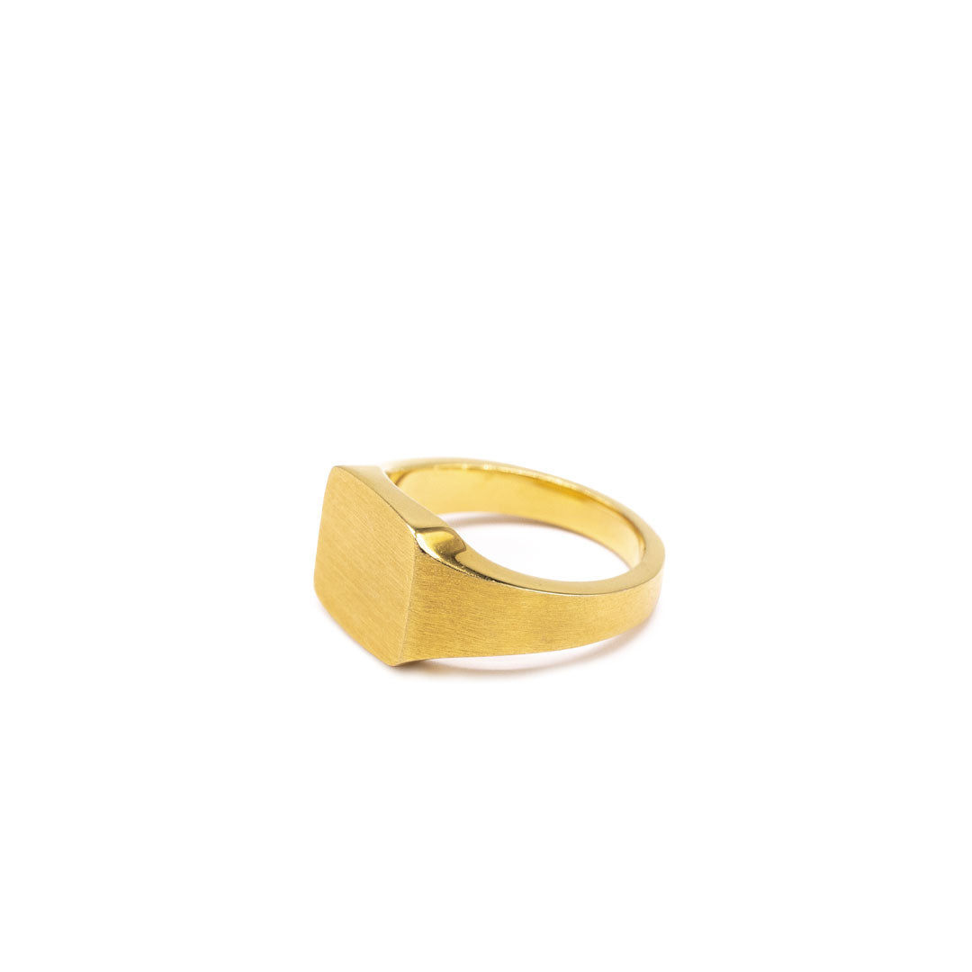 Gold plated Silver ring with a square face and a heavily brushed finishon a white background