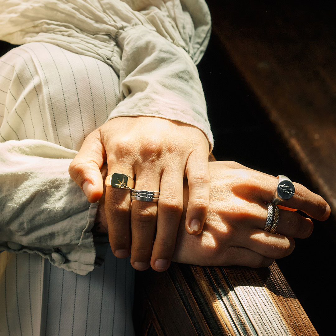 Close-up of two hands with rings on a wooden surface