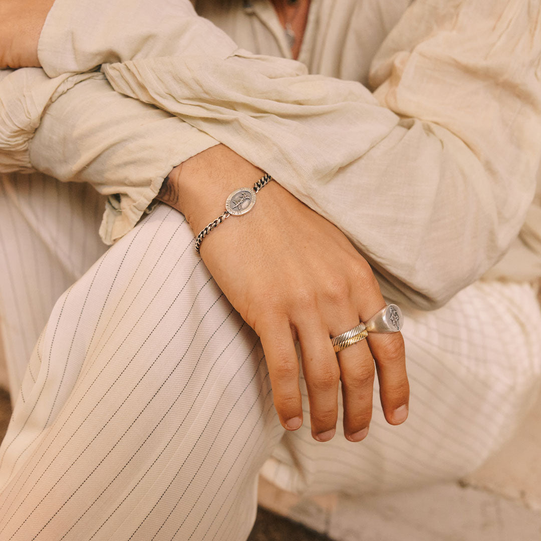 Close-up of a person's hand wearing two rings with a neutral background