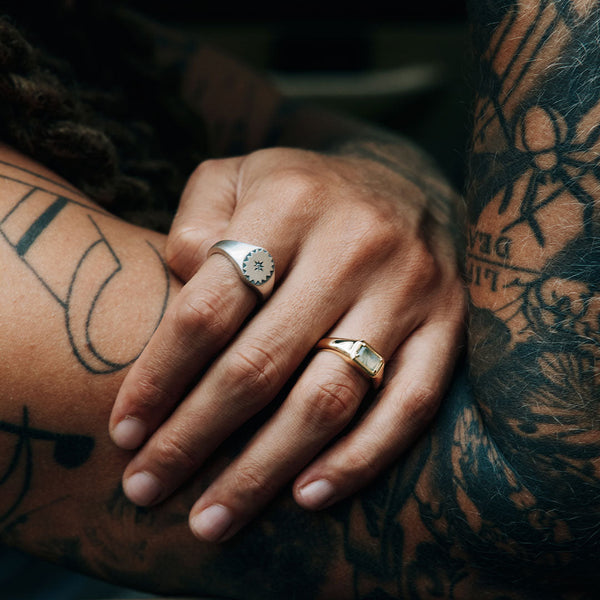 Close-up of a hand with tattoos wearing two rings.
