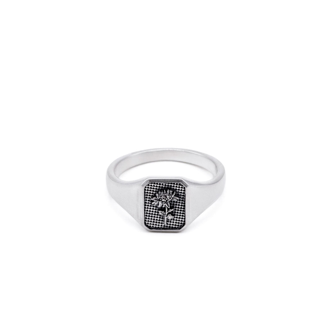 Silver ring with a flower inside a rectangle shaped face on a white background by Serge DeNimes