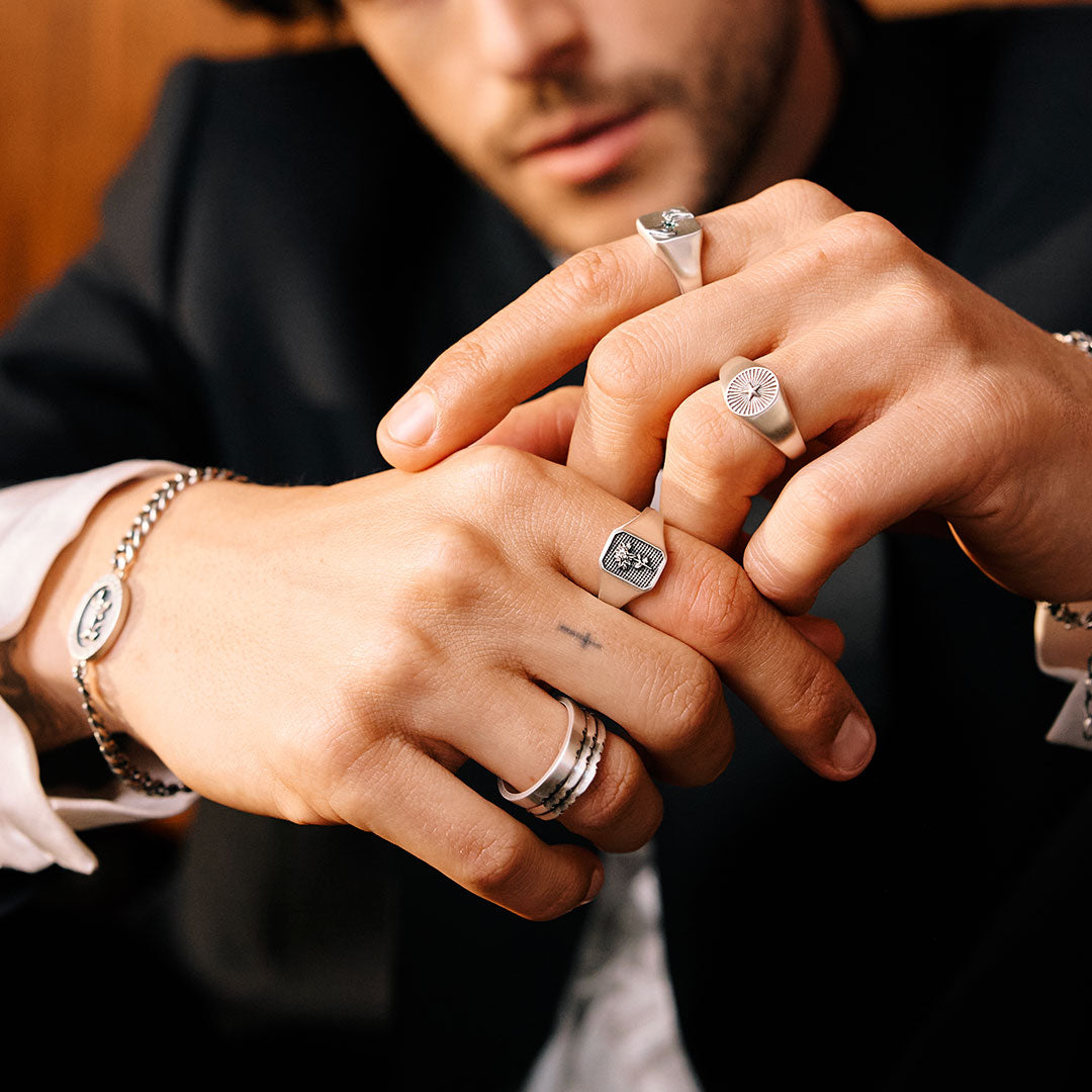 Close-up of hands with multiple rings and bracelets, focusing on jewelry details.