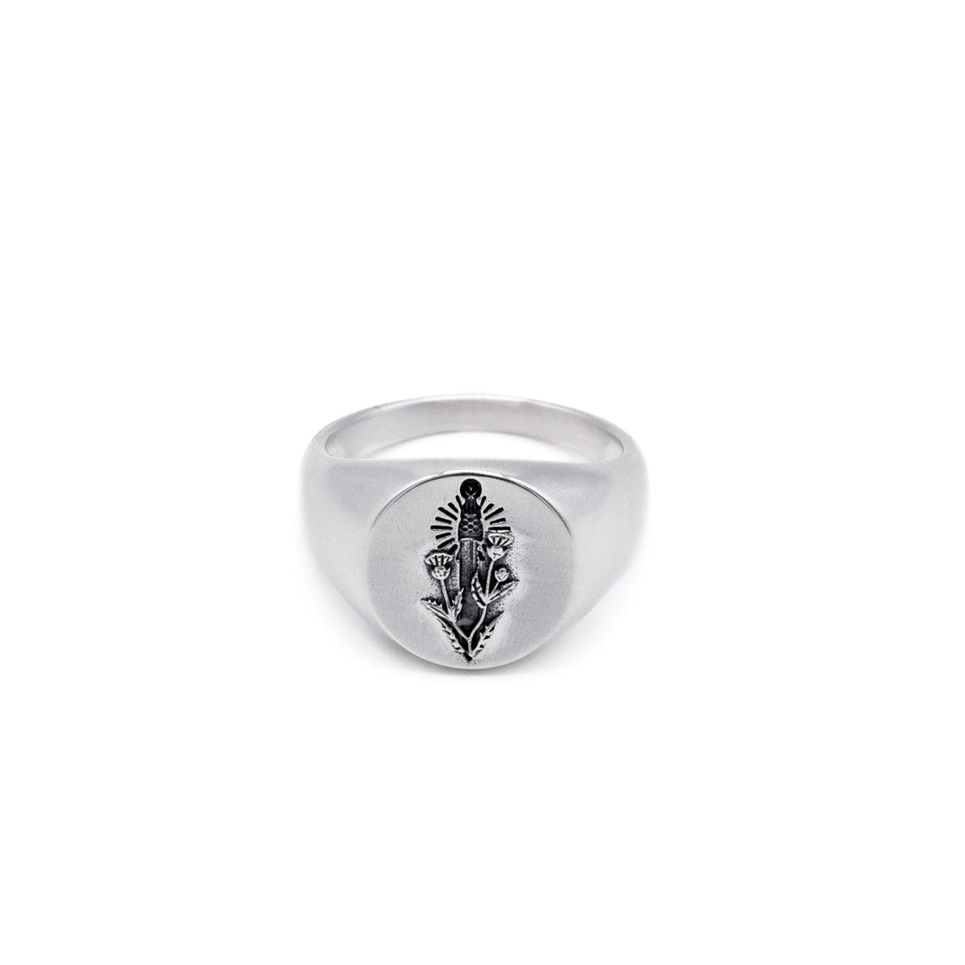 Silver oval ring with a thistle and sword design on a white background