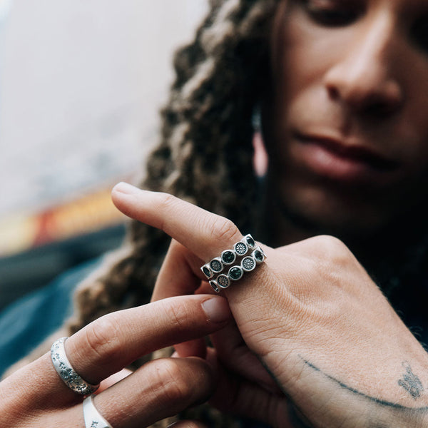 Person wearing multiple silver rings on fingers with a blurred background