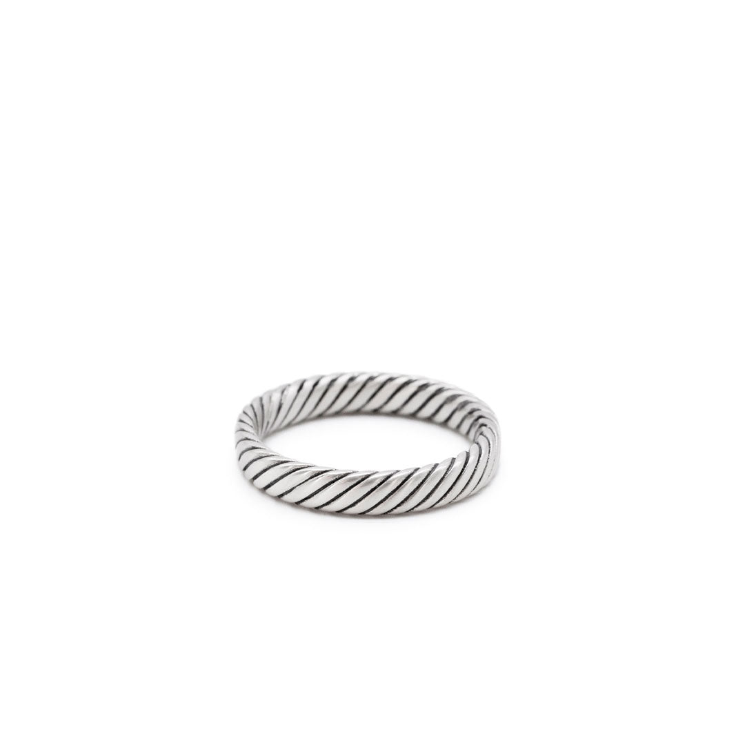 Silver band ring with a twist detail on a white background by Serge DeNimes