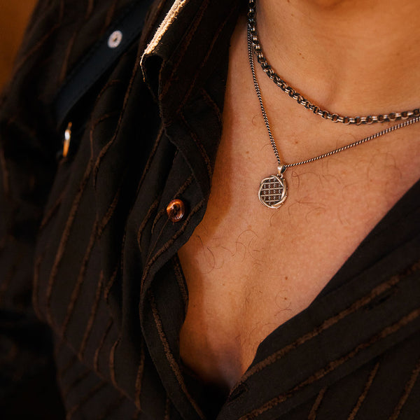 Close-up of a person wearing a necklace with a unique pendant.