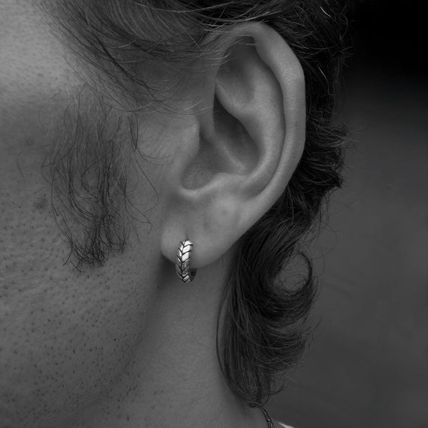 Close-up of an ear with a small hoop earring on a dark background