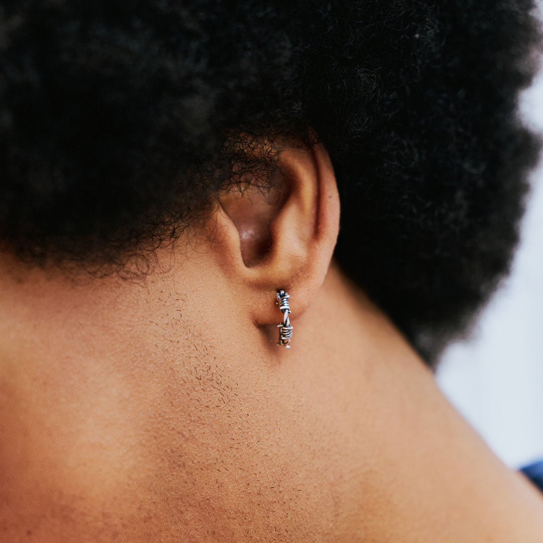 Close-up of an ear with a small hoop earring, focusing on the jewelry.