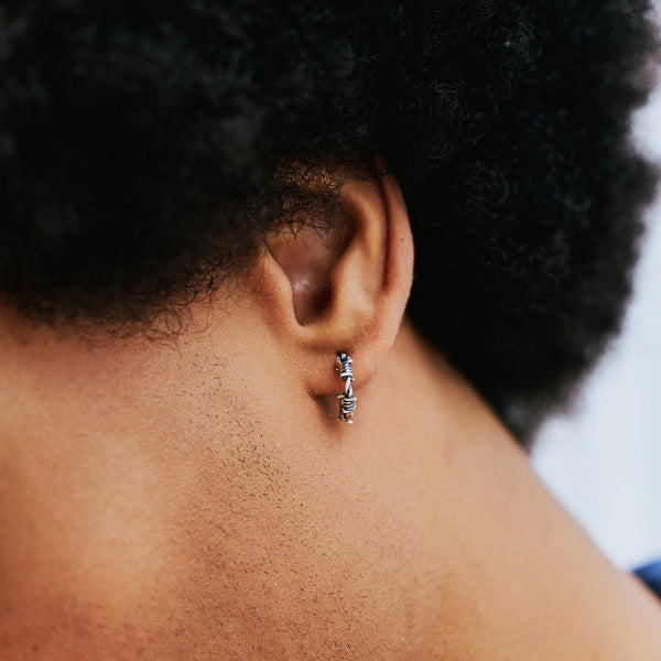 Close-up of an ear with a small hoop earring, focusing on the jewelry.