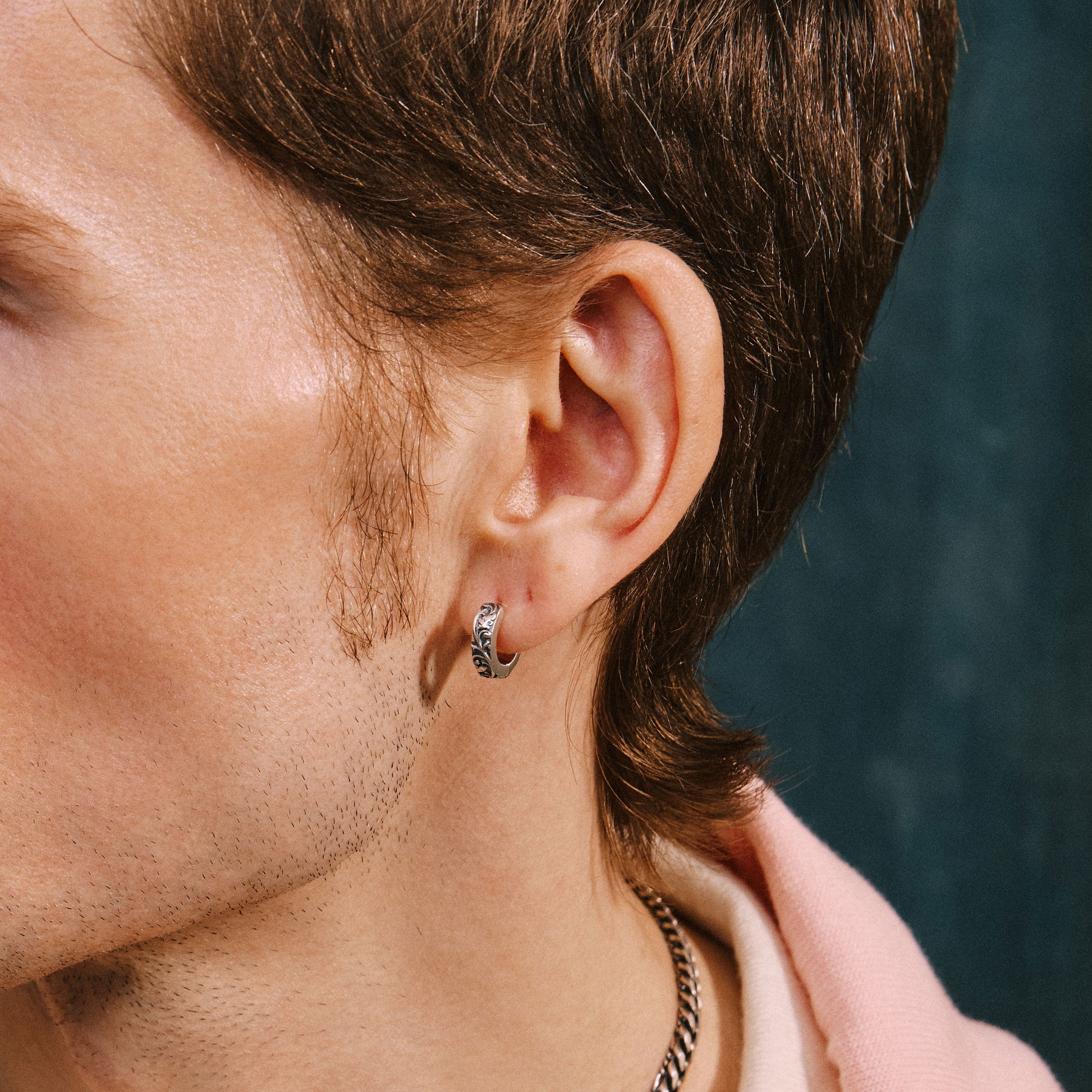 Close-up of a person wearing a silver hoop earring with a blurred background